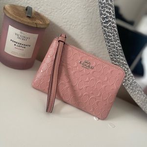 Woman’s Pink Coach wristlet in signature leather